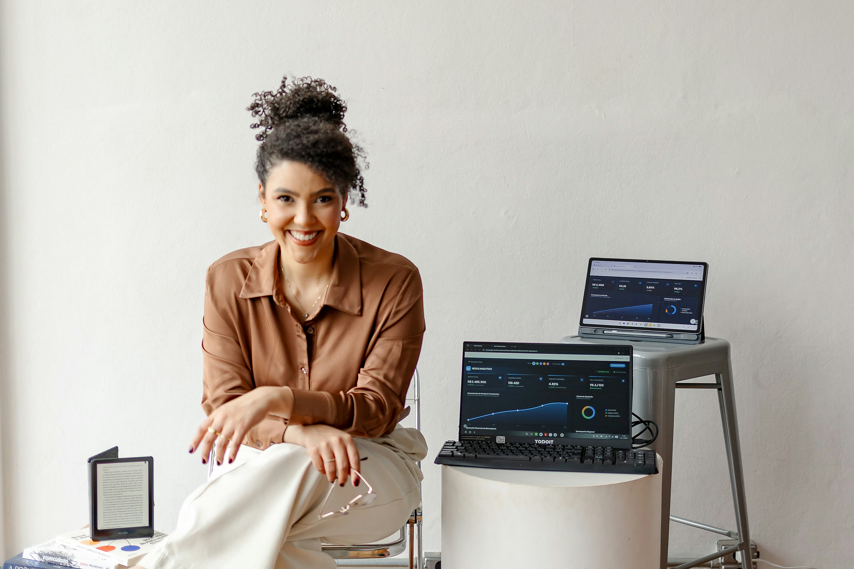 Fernanda Machado sorrindo ao lado de notebooks com dashboards de dados